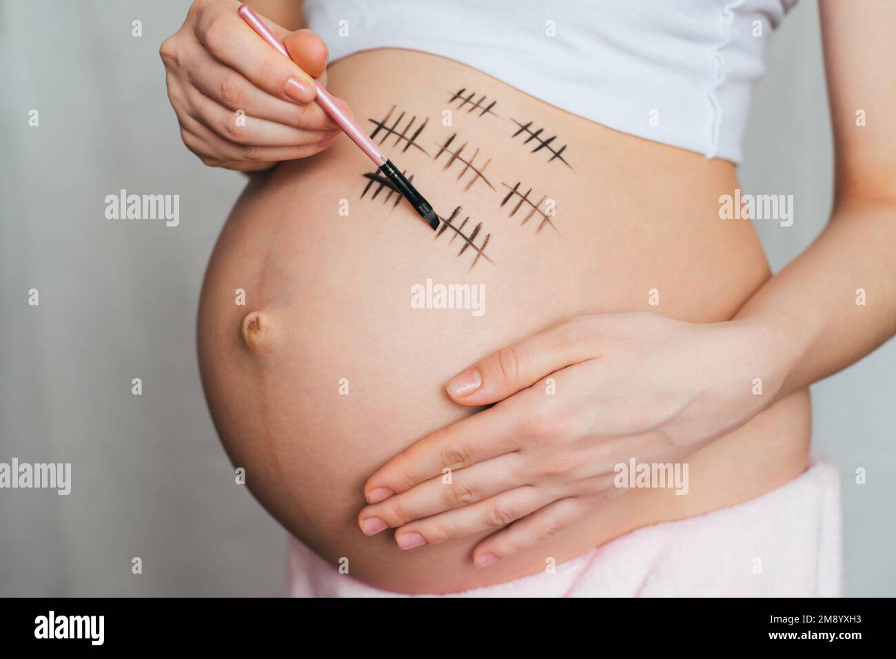 pregnant girl paints pregnancy term on her belly closeup Stock Photo