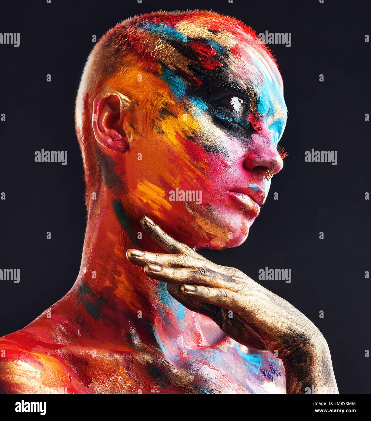 Weird but beautiful. an attractive young woman posing alone in the studio with paint on her face and body. Stock Photo