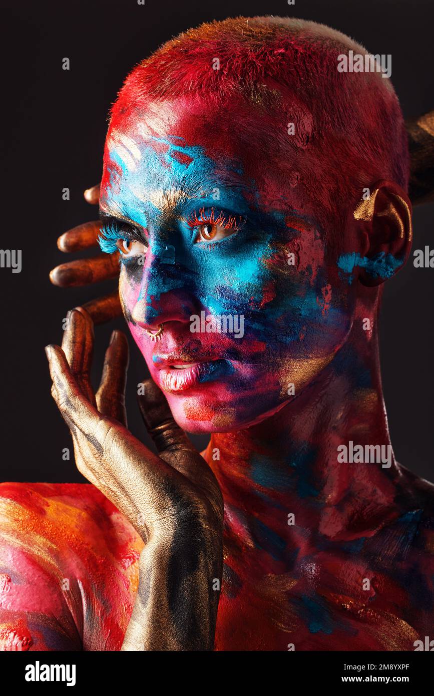 Never hide your madness. an attractive young woman posing alone in the studio with paint on her face and body. Stock Photo