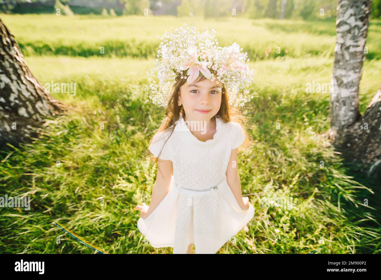happy young girl with a wreath of flowers on her head and a white dress ...