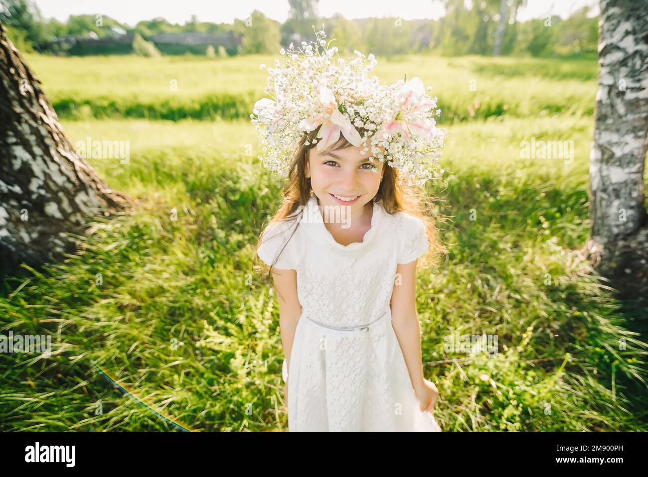 happy young girl with a wreath of flowers on her head Caucasian appearance smiling in the summer outdoors Stock Photo