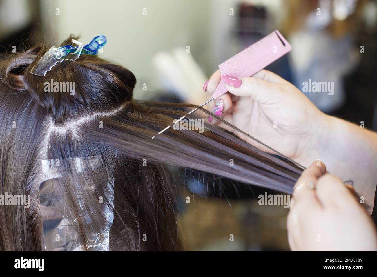 The hairdresser paints a woman's hair in the beauty salon