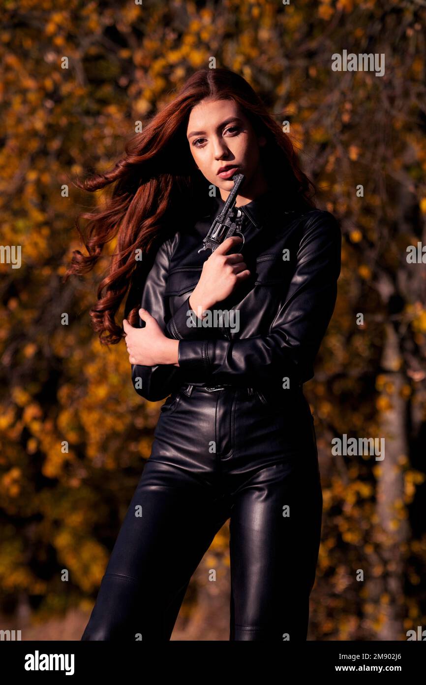 A Caucasian woman wearing black costume and holding gun Stock Photo