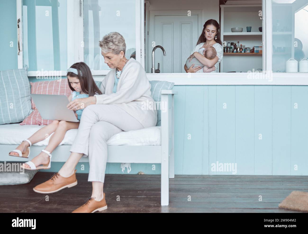 Well watch while we wait for mom. a mature woman bonding with her granddaughter while a mother holds her newborn in the background. Stock Photo