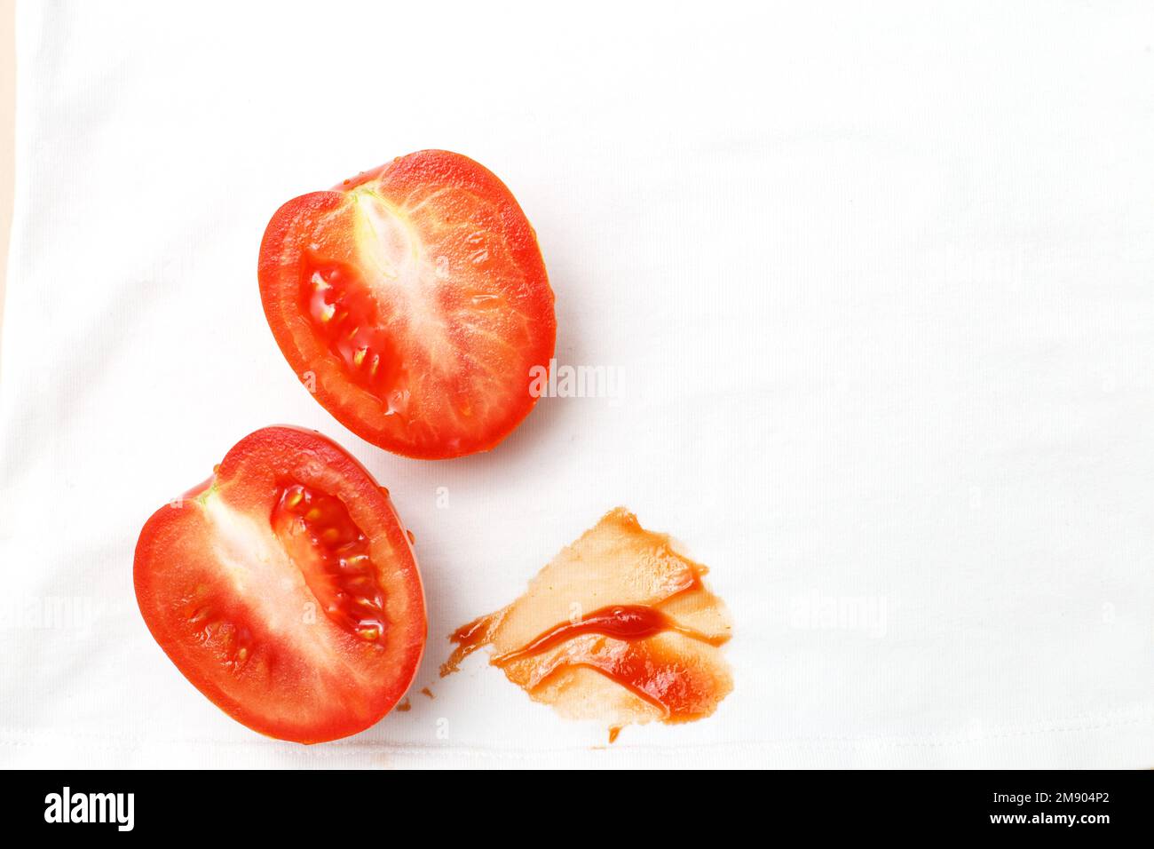 Tomatoes and ketchup stain on white shirt clothes. Stock Photo