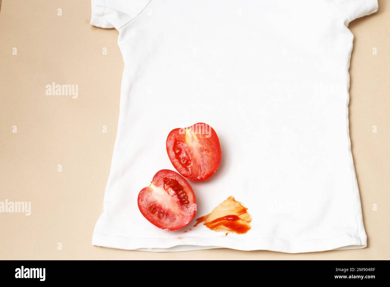 Tomatoes and ketchup stain on white shirt clothes on a beige background