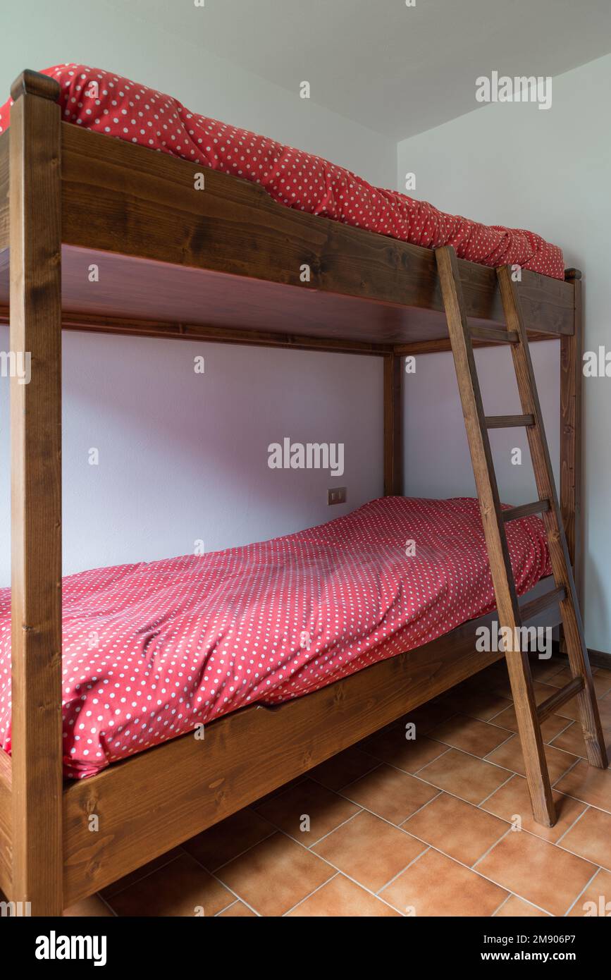 Wooden bunk bed with ladder in an empty room Stock Photo