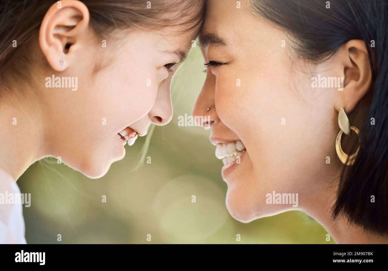 Be the reason she smiles. an adorable little girl and her mother looking at each other face to face in a garden. Stock Photo