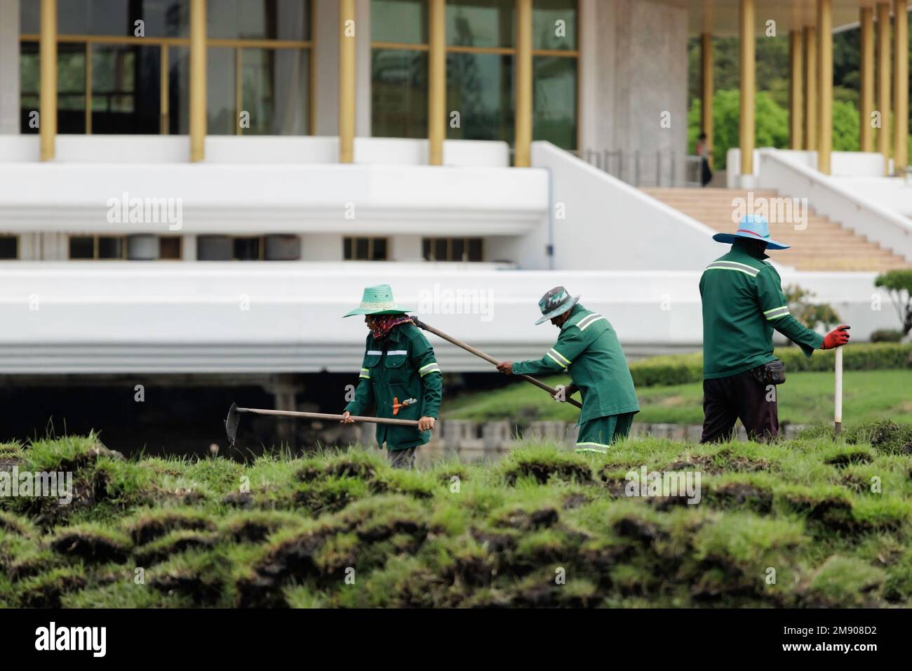 Bangkok, Thailand - October 12, 2020 : Asian gardener man and woman worker working and digging soil to prepare planting grass in the city park. Stock Photo