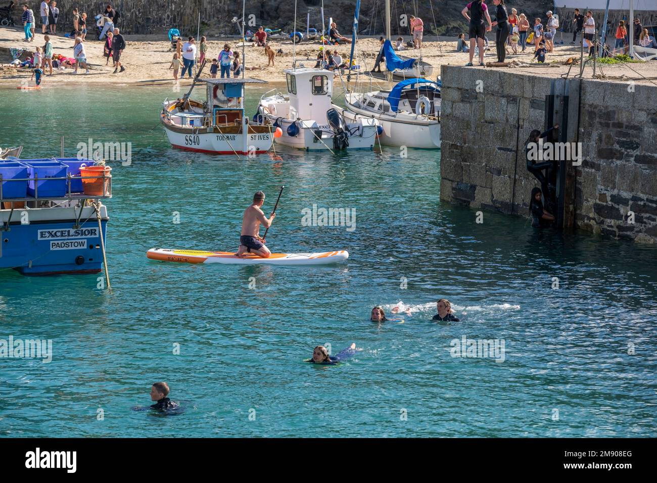Summer holidaymakers enjoying themselves at high tide in Newquay Harbour in Cornwall in the UK. Stock Photo
