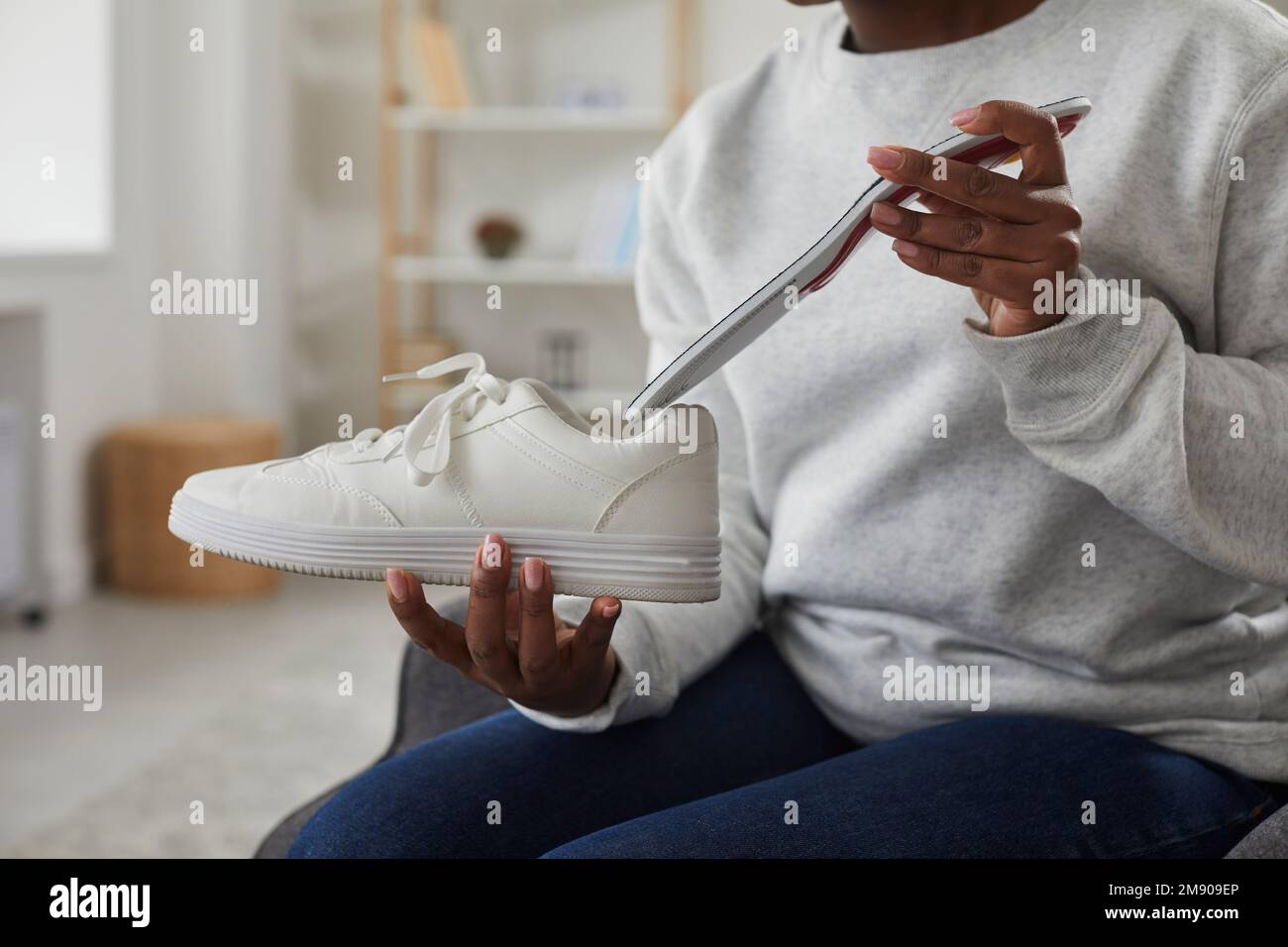 Plug The Insole African American woman inserting an insole into a sneakers at home ...