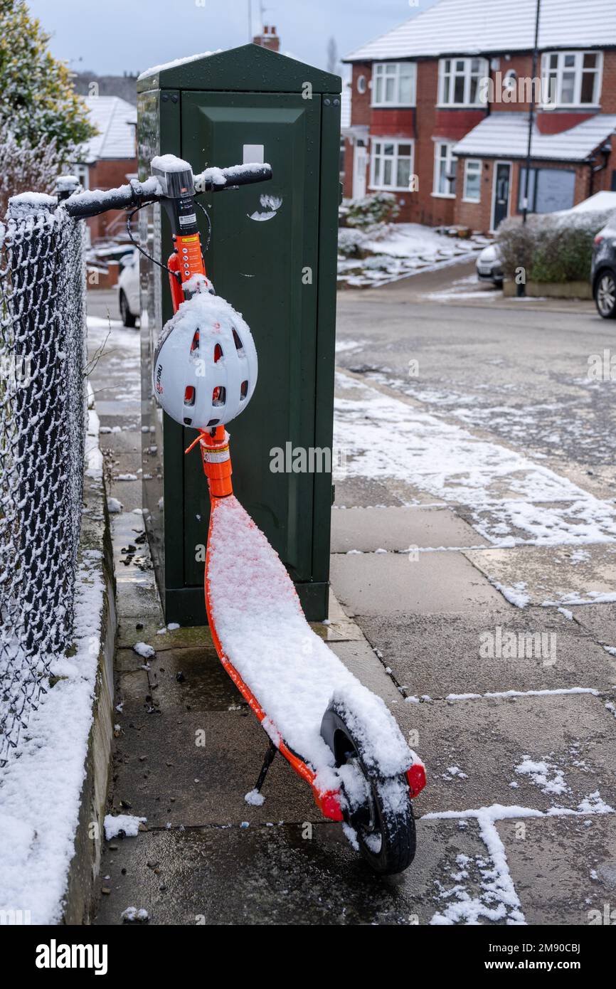 A Neuron e-scooter, in Newcastle upon Tyne, UK, parked on the pavement is covered in snow. Concept of winter travel. Stock Photo