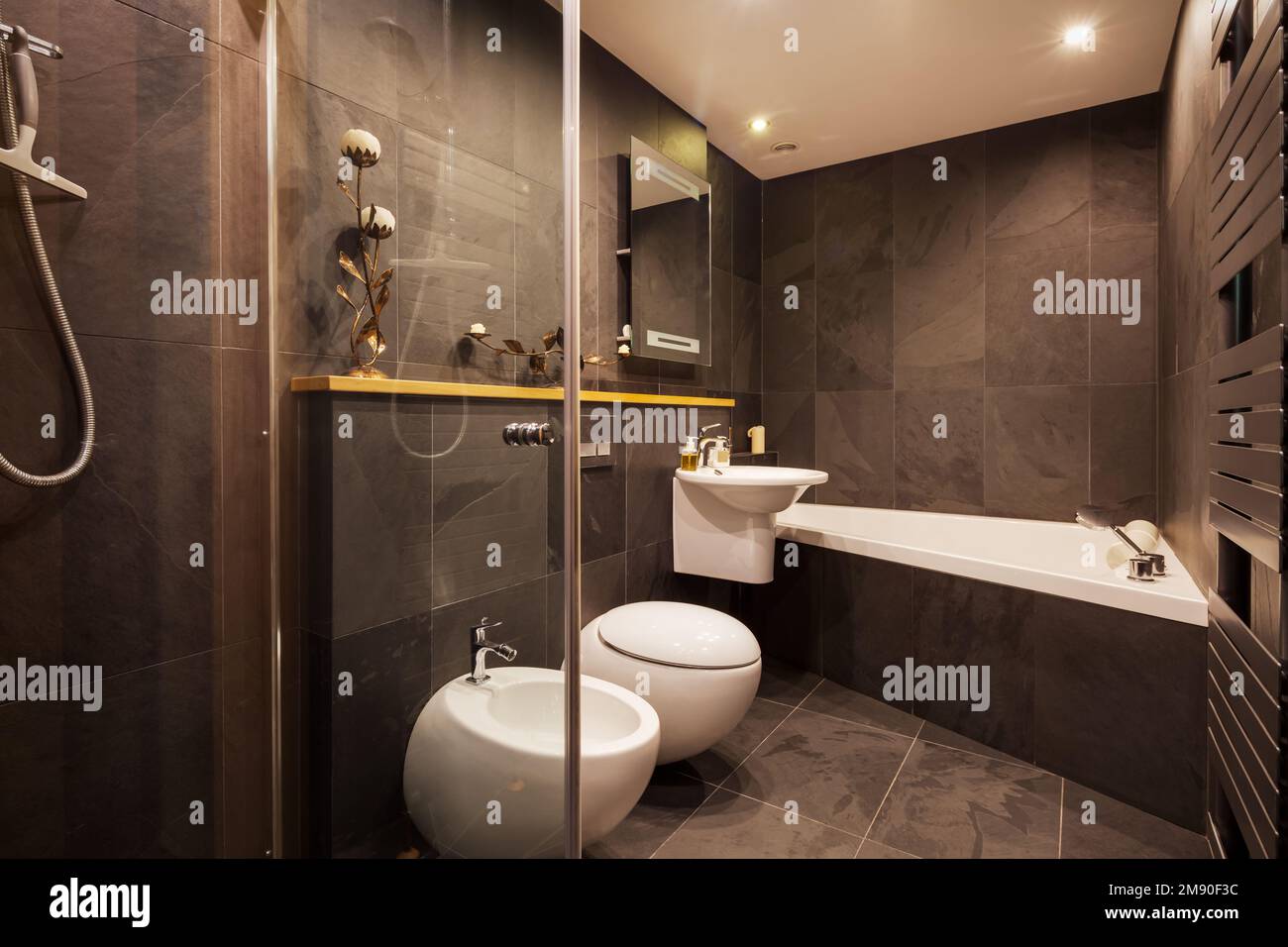 Contemporary modern tiled bathroom with dark tiled walls, heated towel