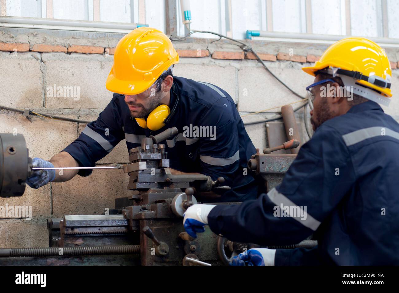 Engineer man training with foreman for apprentice using lathe, apprenticeship teaching with worker, technician and learning, inspector and labor, inte Stock Photo