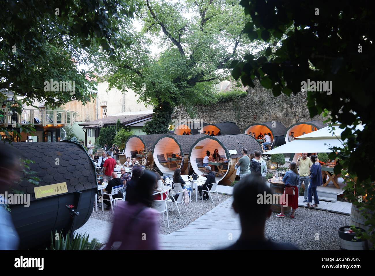 Guests sitting in cylindrical tubes covered w/ roof tiles outside a cafe restaurant (Comanda La Bar);they are dry and can eat & drink even if it rains Stock Photo