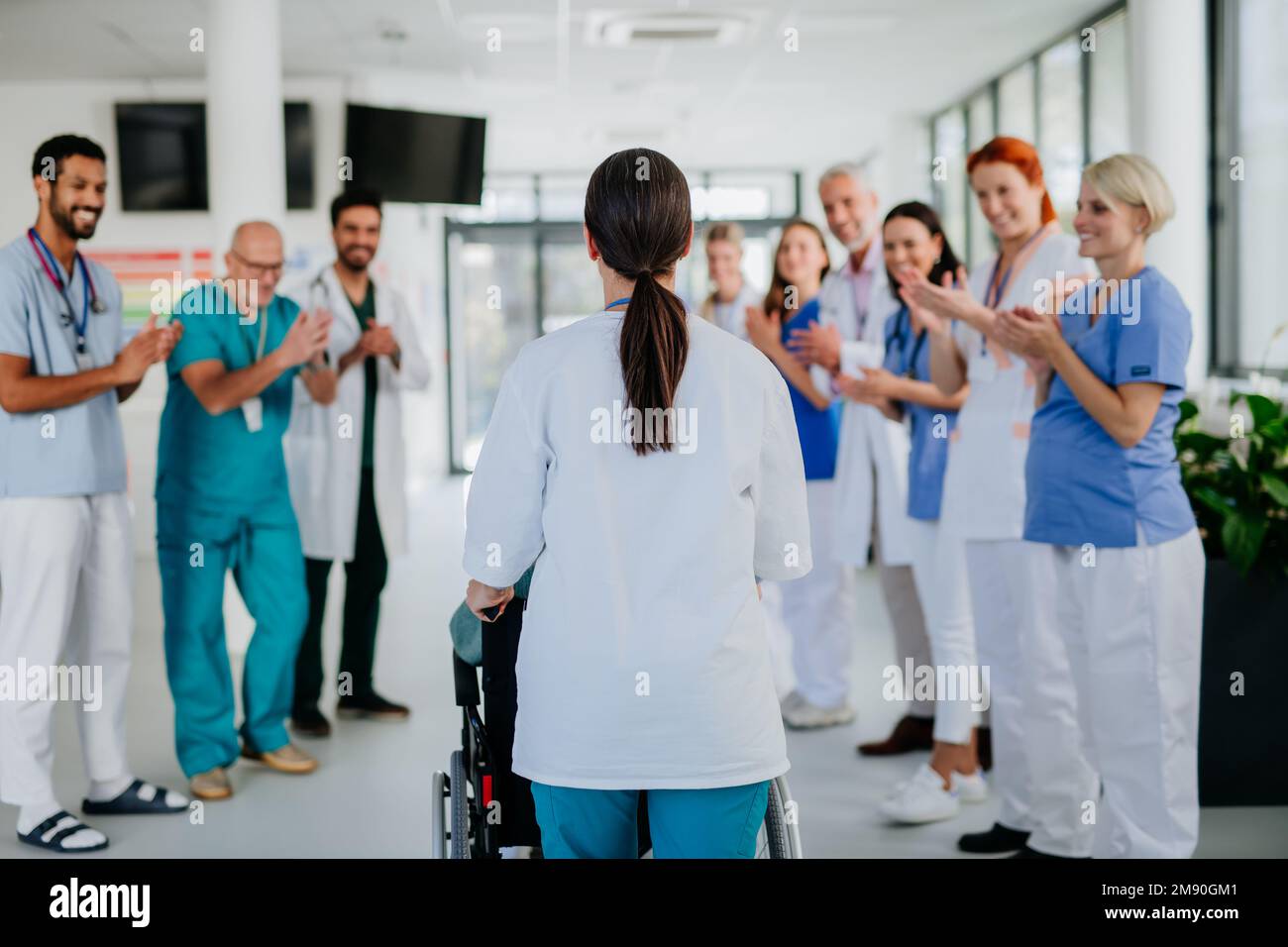 Medical staff clapping to senior patient who recovered from serious illness. Stock Photo