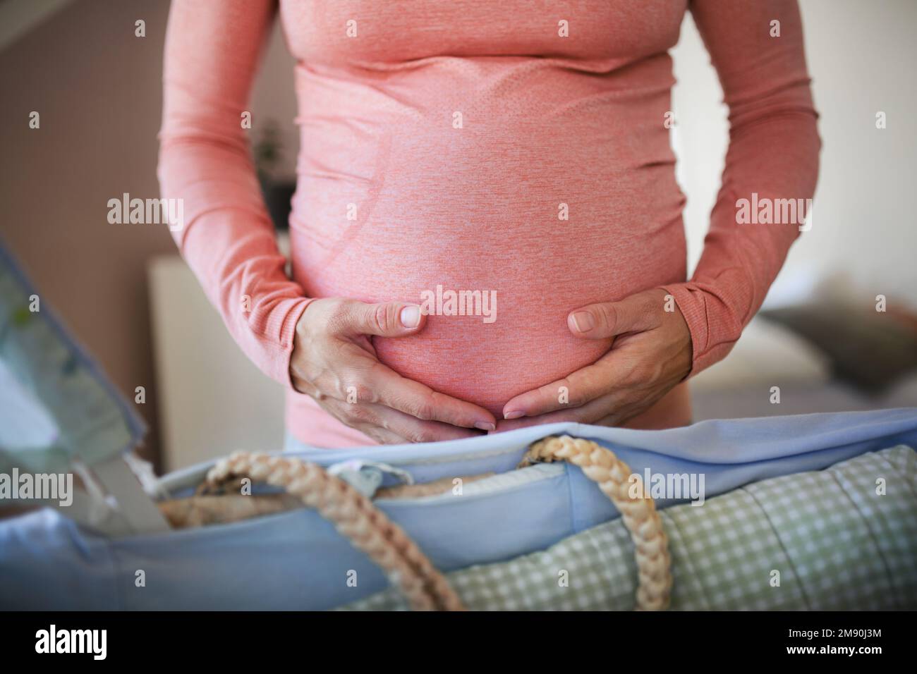 Close-up of pregnant woman preparing for baby, stroking her belly. Stock Photo