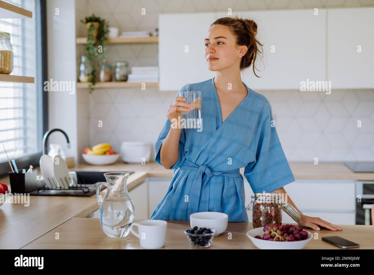 Young woman preparing muesli for breakfast in her kitchen, morning