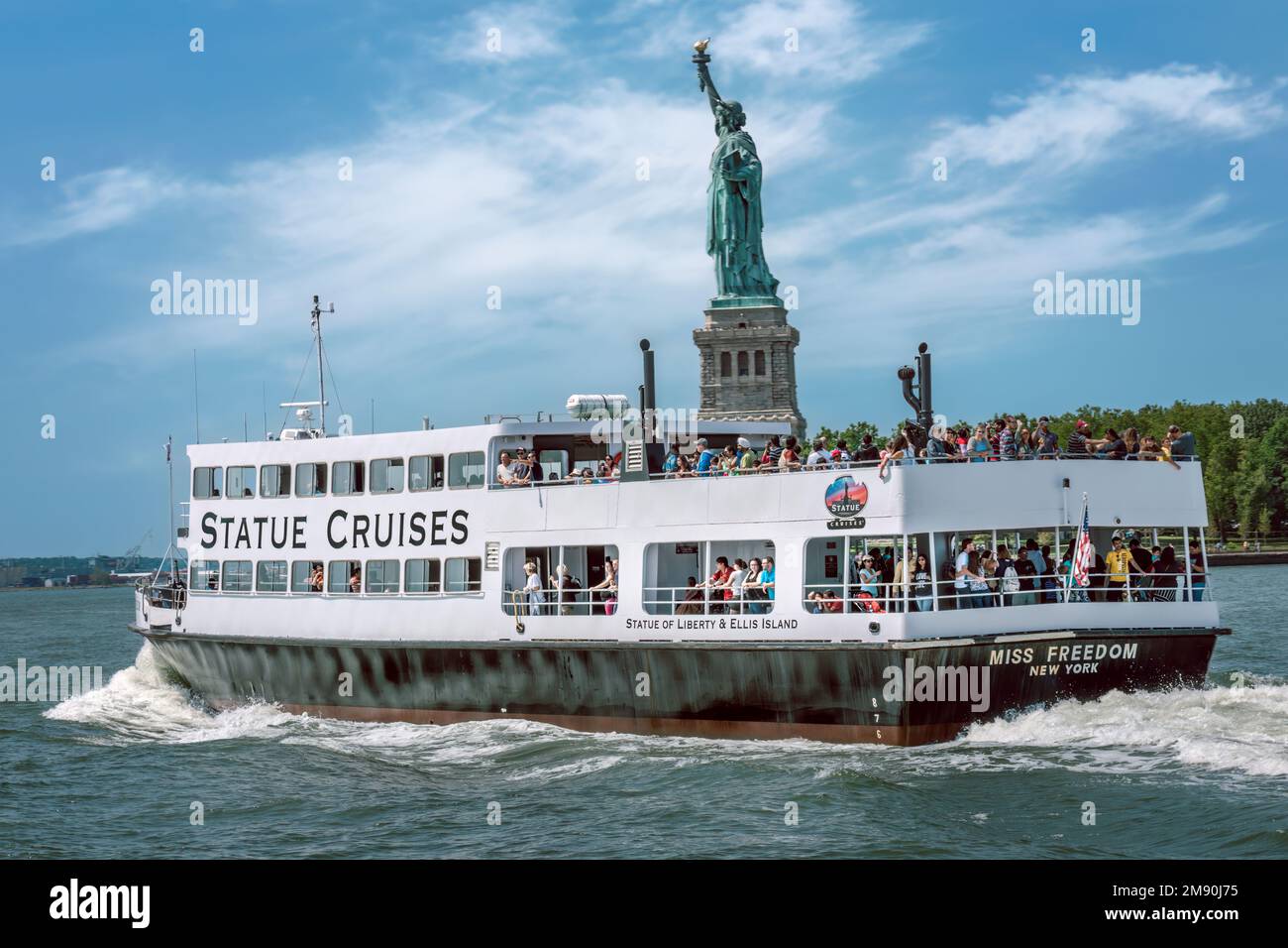 A sightseeing cruise along the Hudson River heads towards the Statue of Liberty and Ellis Island just off the coast of New York in the United States o Stock Photo