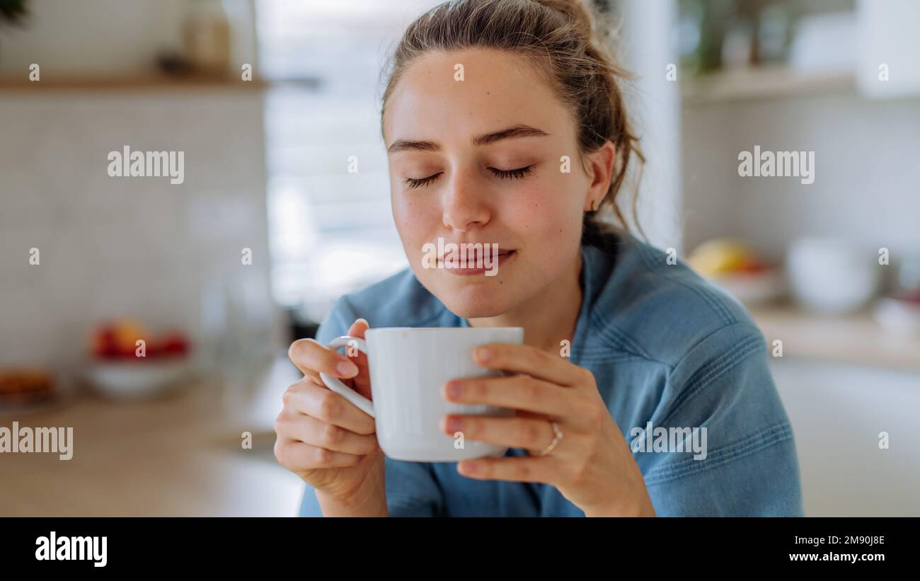 Young woman enjoying cup of coffee at morning, in her kitchen. Stock Photo