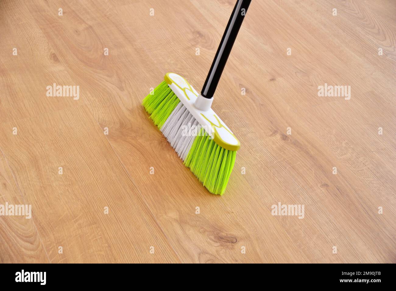 housework, cleaning and housekeeping concept - close up of  broom sweeping floor at home Stock Photo