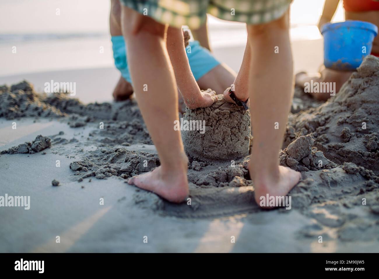 Close-up of children playing on the beach, building sand castle. Stock Photo
