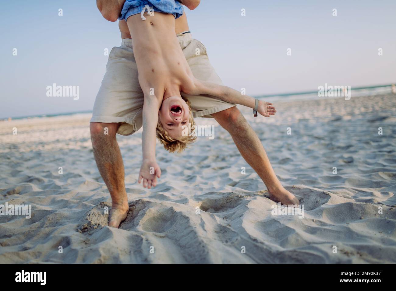 Father holding his son upside down, enjoying summer vacation, having fun. Stock Photo