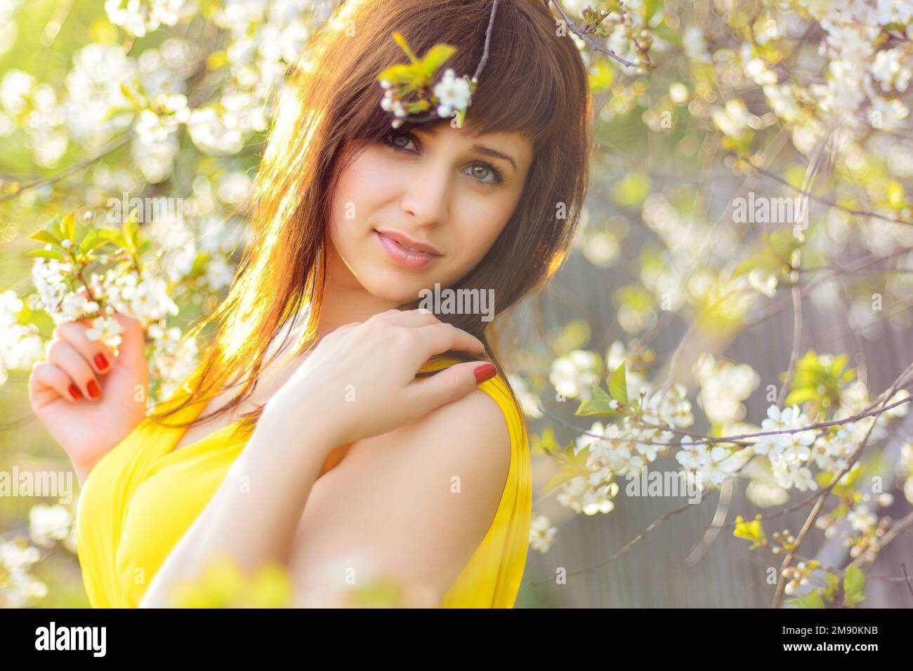 young cute girl in yellow dress in spring on cherry blossom background