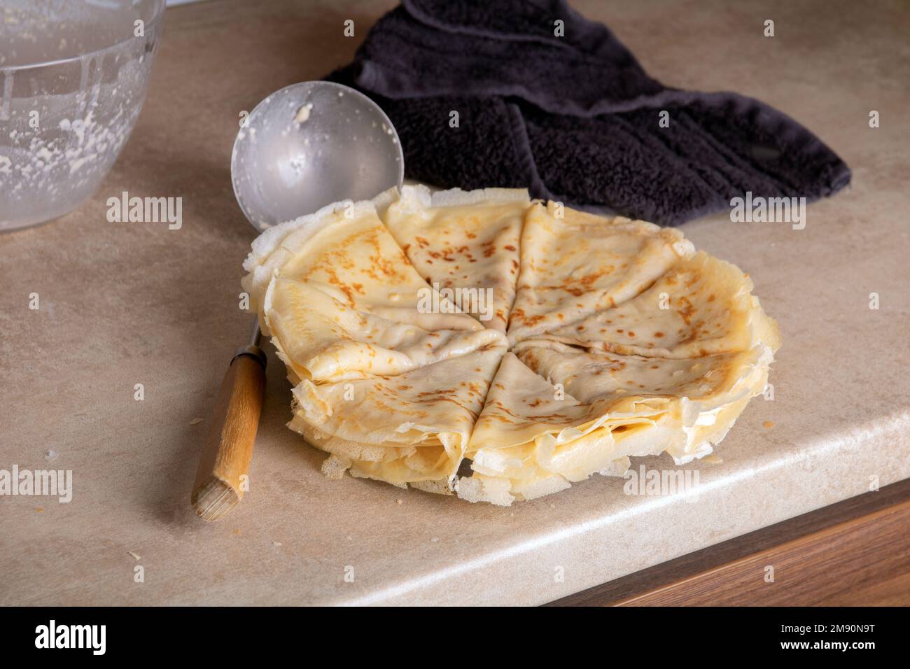 photo ladle pancake plate and towel on the kitchen table Stock Photo
