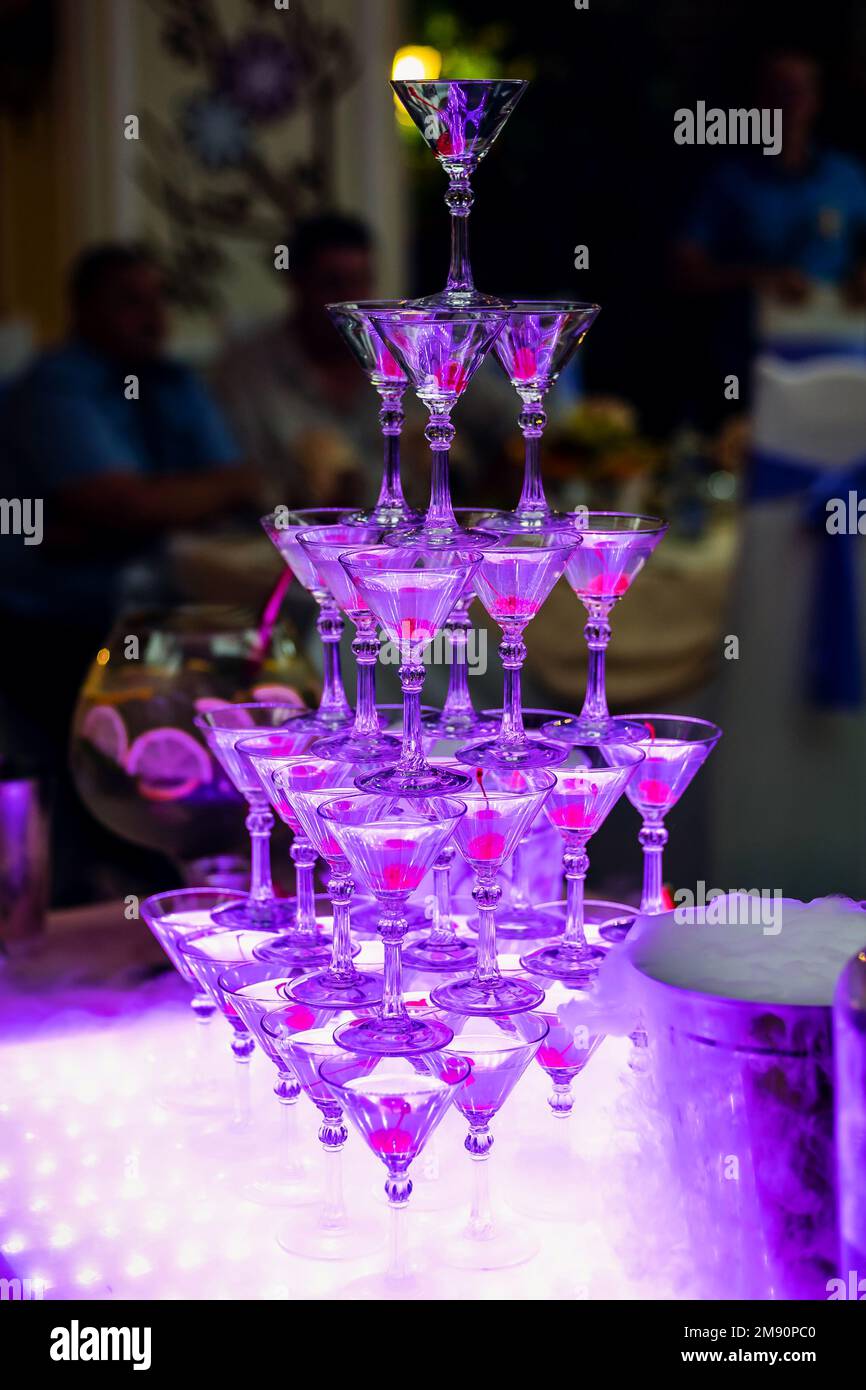tower of Martini glasses in the restaurant for the bartender show with purple lights Stock Photo