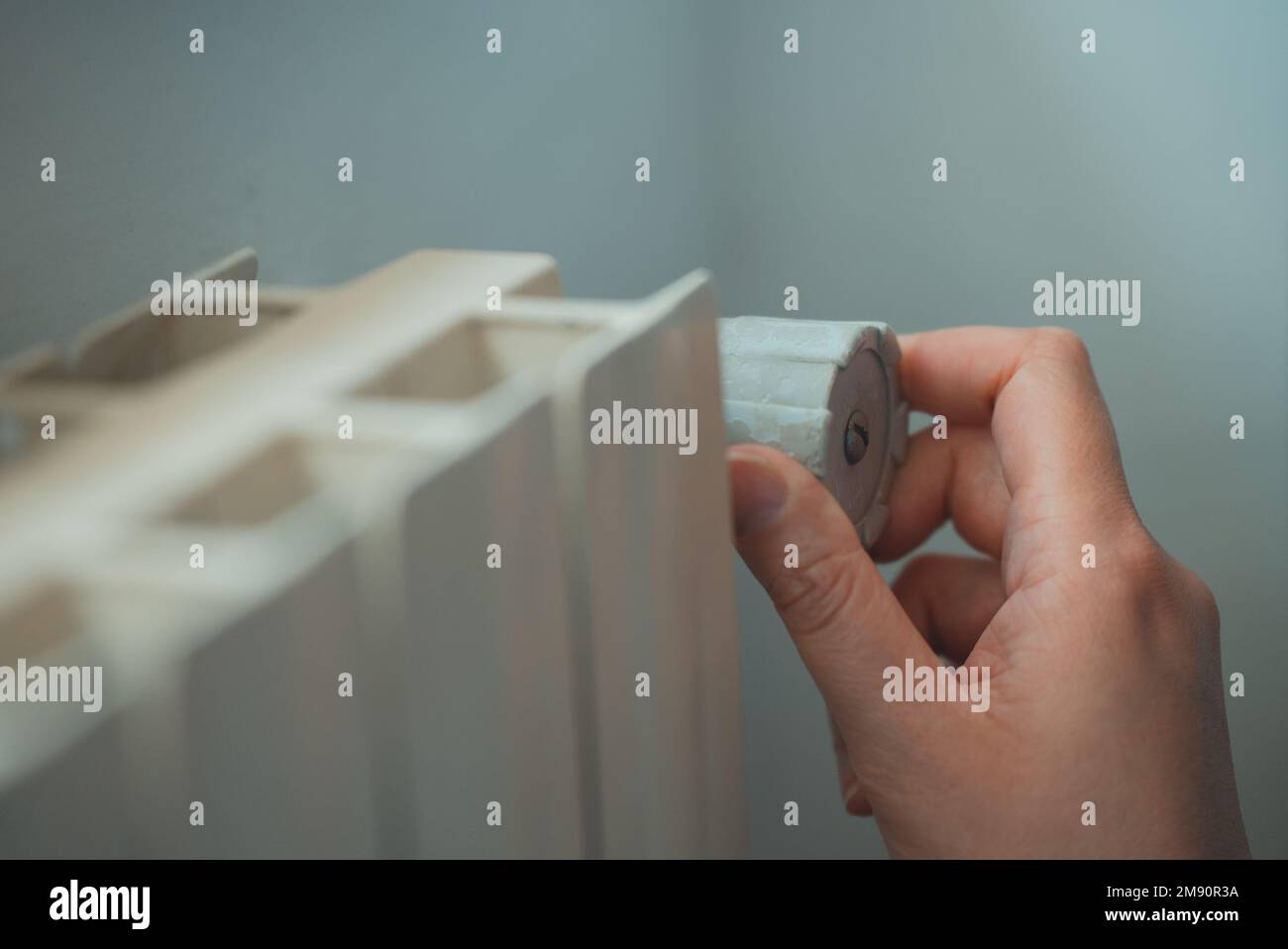 Female hand adjusting thermostat to turn on the radiator heater at home ...