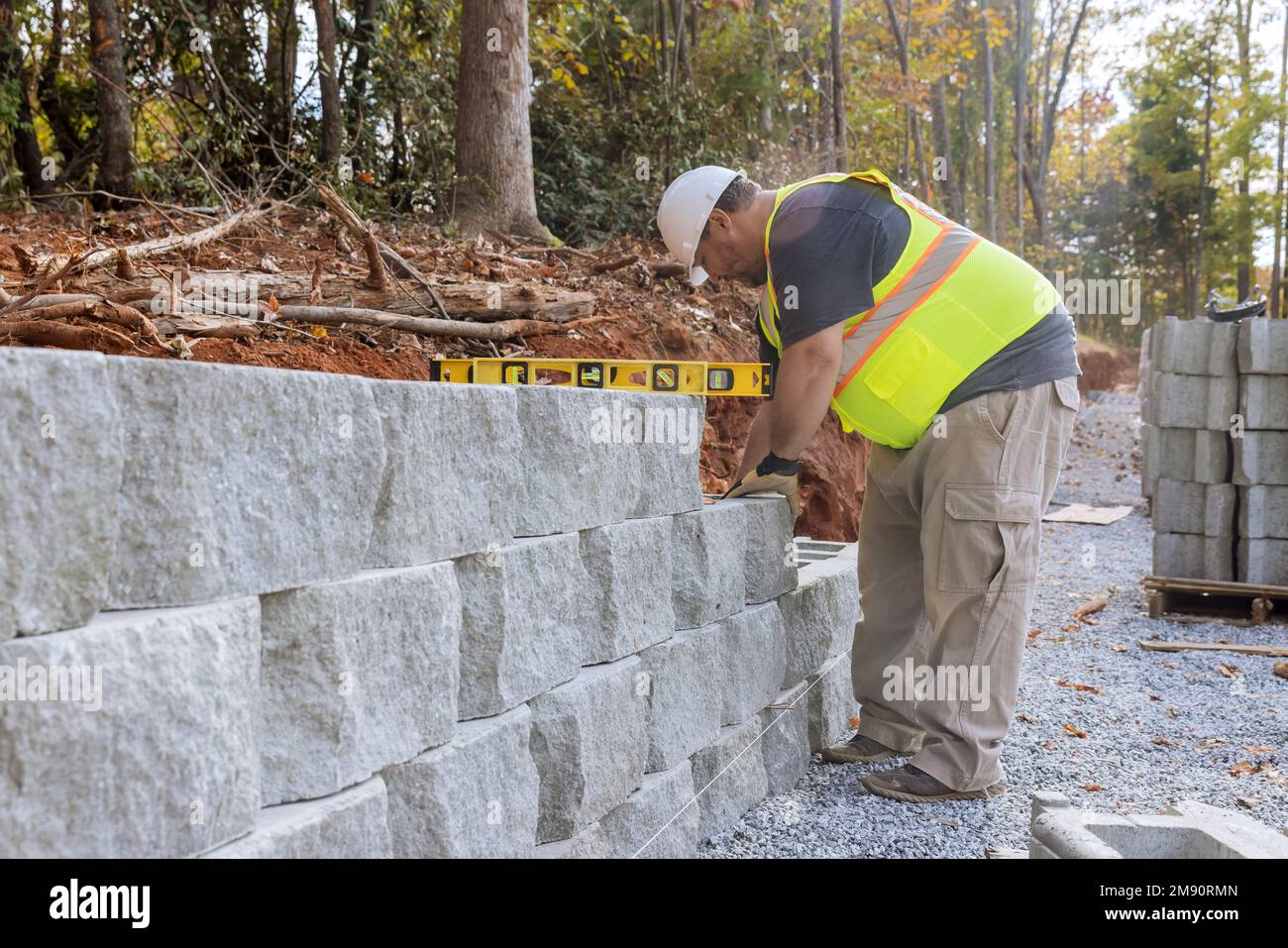 Construction worker building retaining block wall being built on new