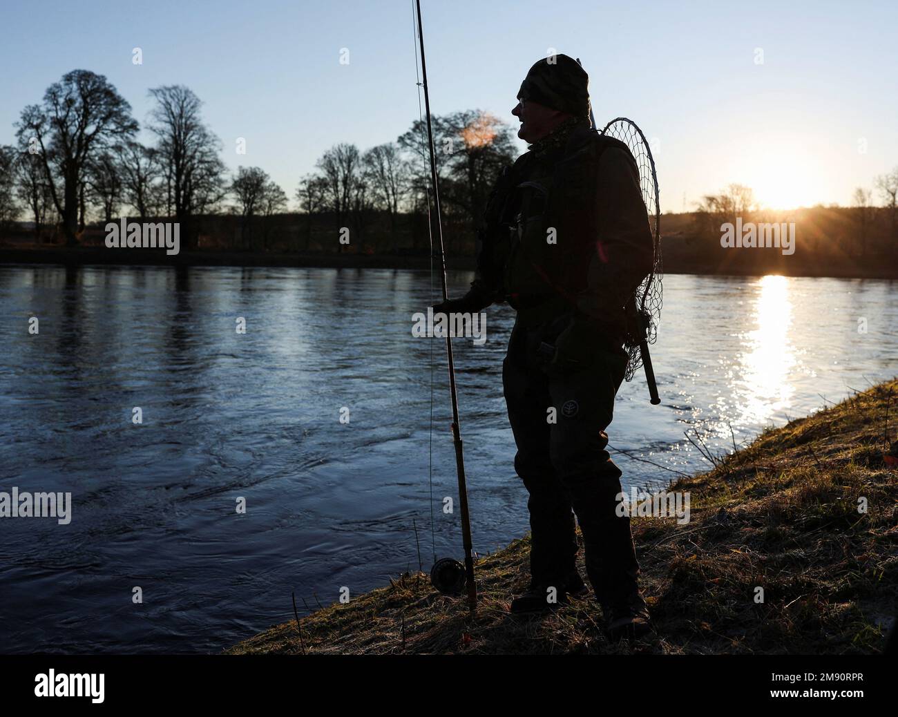 An angler waits on the bank on the opening day of the salmon fishing season on the river Tay at Meikleour fisheries, Scotland, Britain, January 16, 2023. REUTERS/Russell Cheyne Stock Photo
