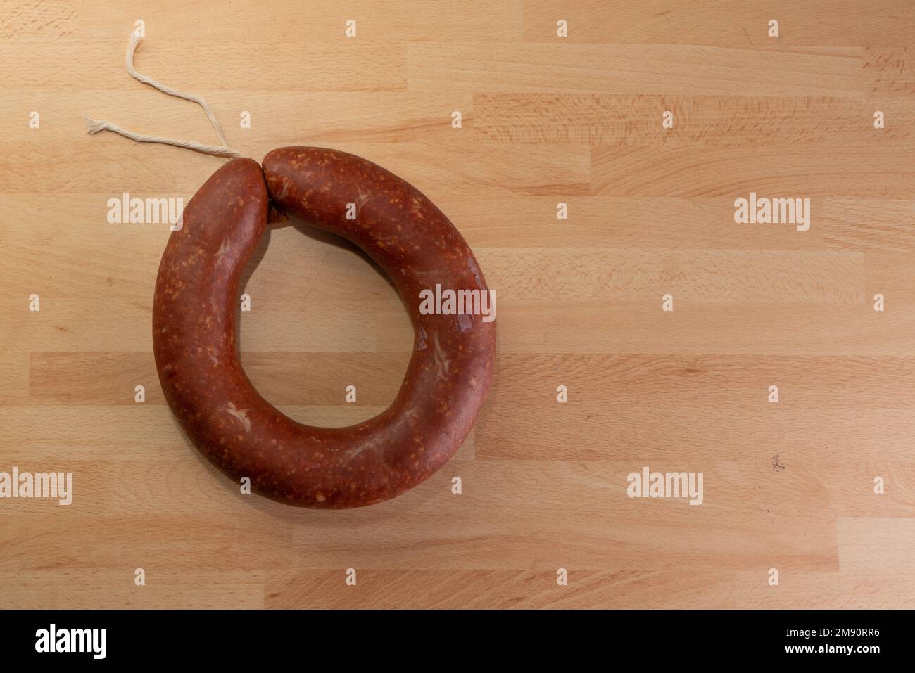 Top view of fermented circular traditional sausage on wooden background with text area. Stock Photo