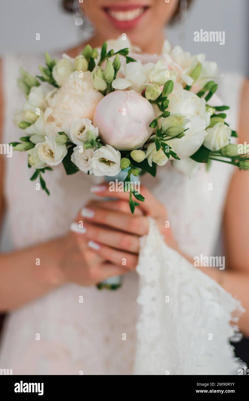 wedding bouquet with white peonies in the hands of the bride with a ...