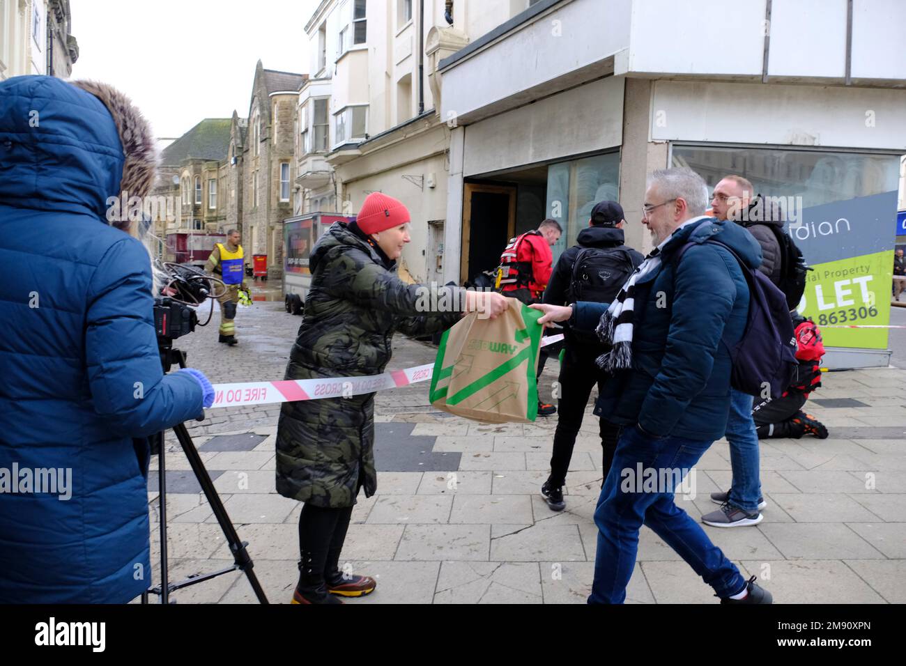 Hastings, East Sussex, 16 January 2023. Heavy rain and blocked storm drain to the sea causes major flood in Hastings Town Centre, closing Priory Meadow shopping centre and flooding homes and businesses. Agi from Subway sandwich shop gives away bread to passers-by. Carolyn Clarke/Alamy Live News Stock Photo