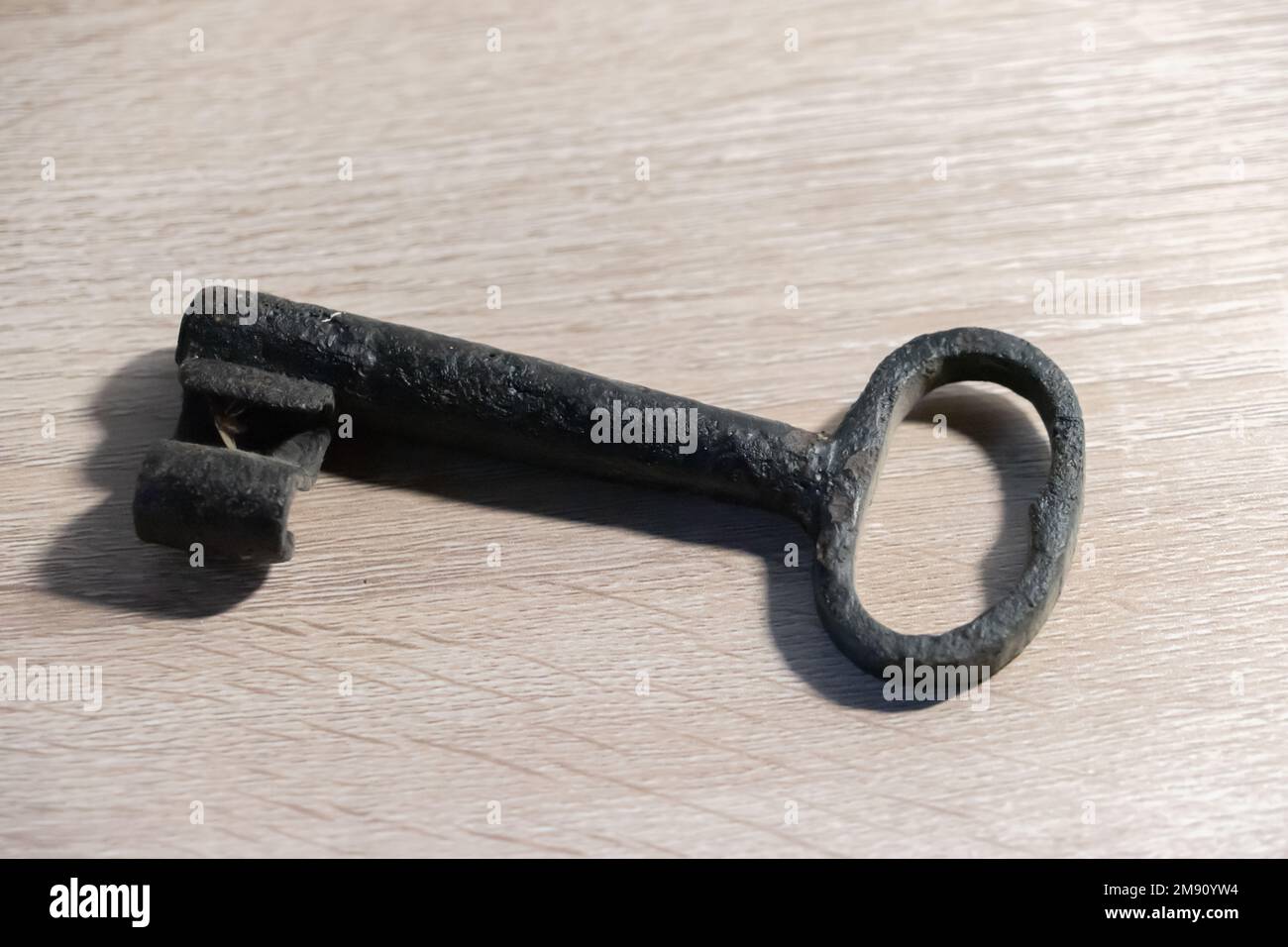 An old rusty key on a wooden table Stock Photo