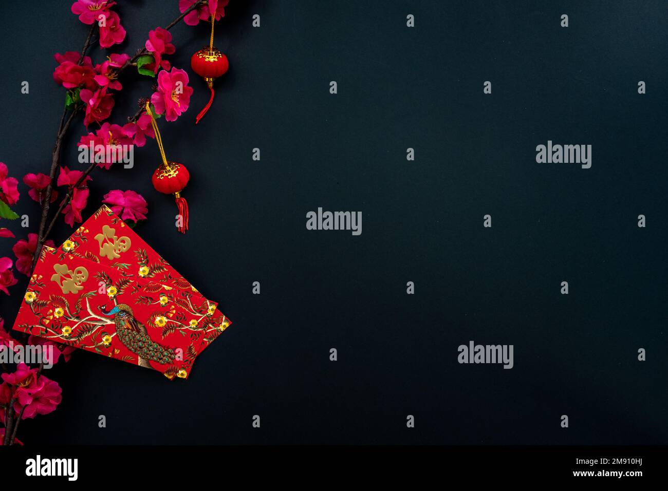 Chinese lunar new year decoration over black background. Flat lay concept with red envelope and plum flower decoration. Stock Photo