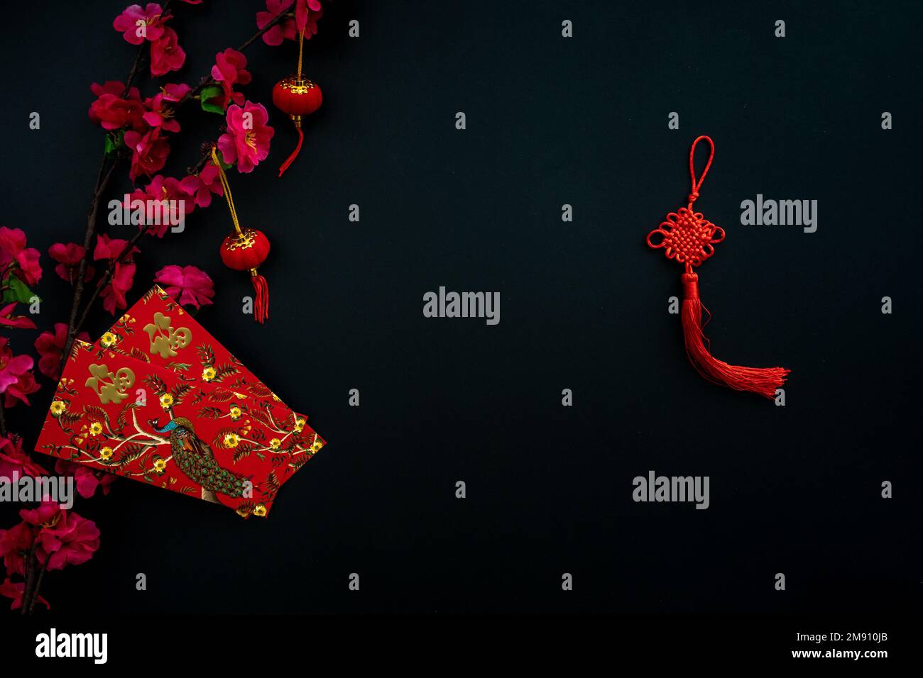 Chinese lunar new year decoration over black background. Flat lay concept with red envelope and plum flower decoration. Stock Photo
