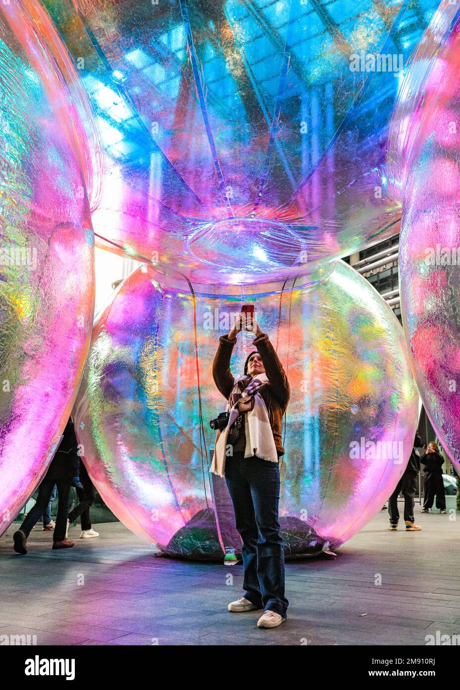 London, UK. 16th Jan, 2023. A visitor from Italy takes pictures of the bubbles. New outdoor art installation 'Evanescent' by Atelier Sisu brings light to the City of London. The iridescent bubbles, which the public can walk under and around, are illuminated at night and are installed outside the iconic Leadenhall Building until the 10th of February. The installation, shown in London for the first time after its premiere in Australia. Evanescent by Atelier Sisu has been commissioned by ECBID and produced by Festival.org. Credit: Imageplotter/Alamy Live News Stock Photo