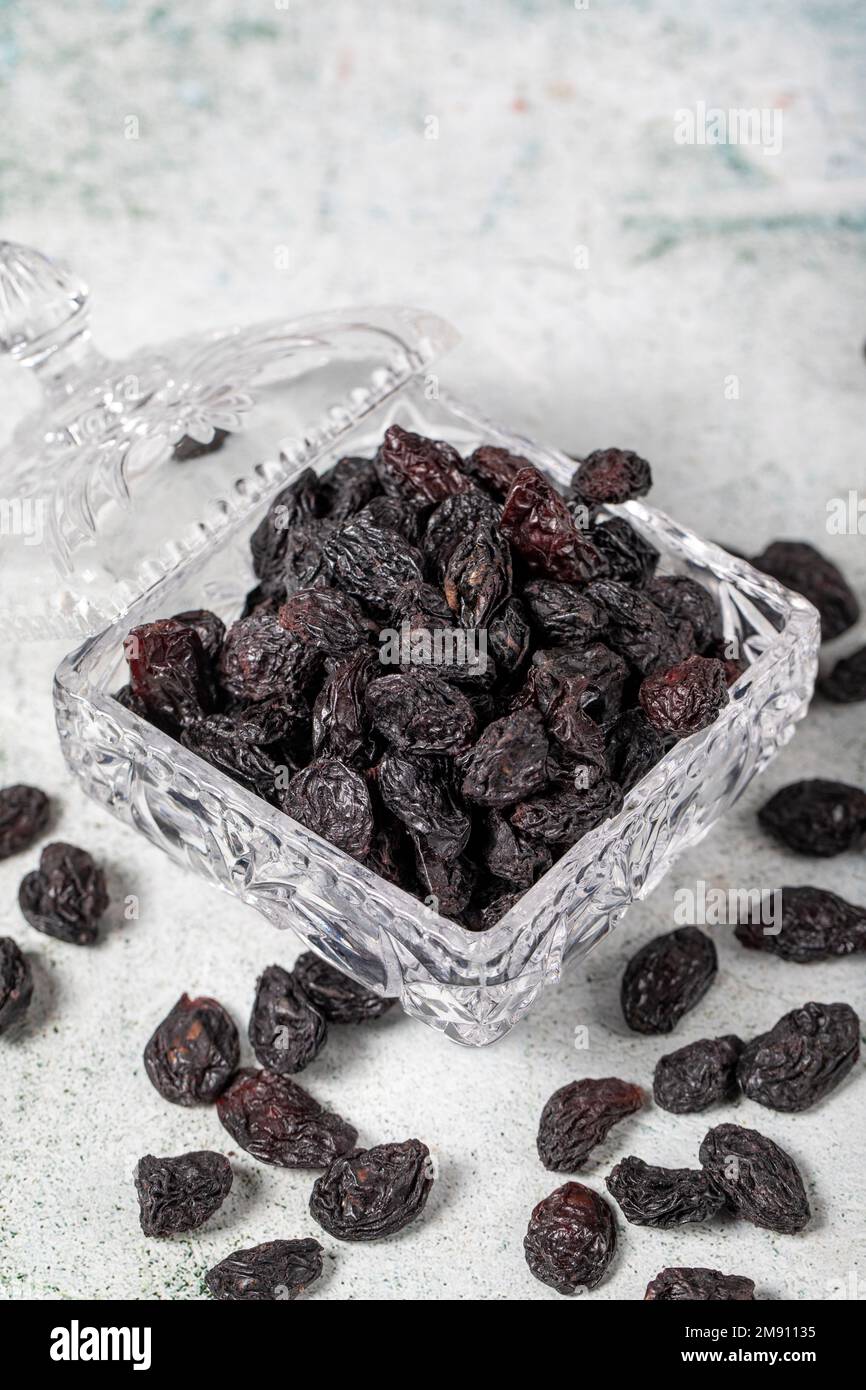 Dried black grapes on stone background. Dried grapes in glass bowl