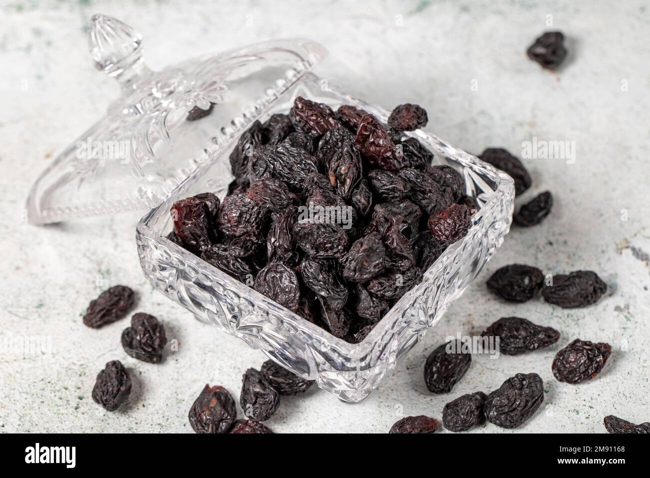 Dried black grapes on stone background. Dried grapes in glass bowl