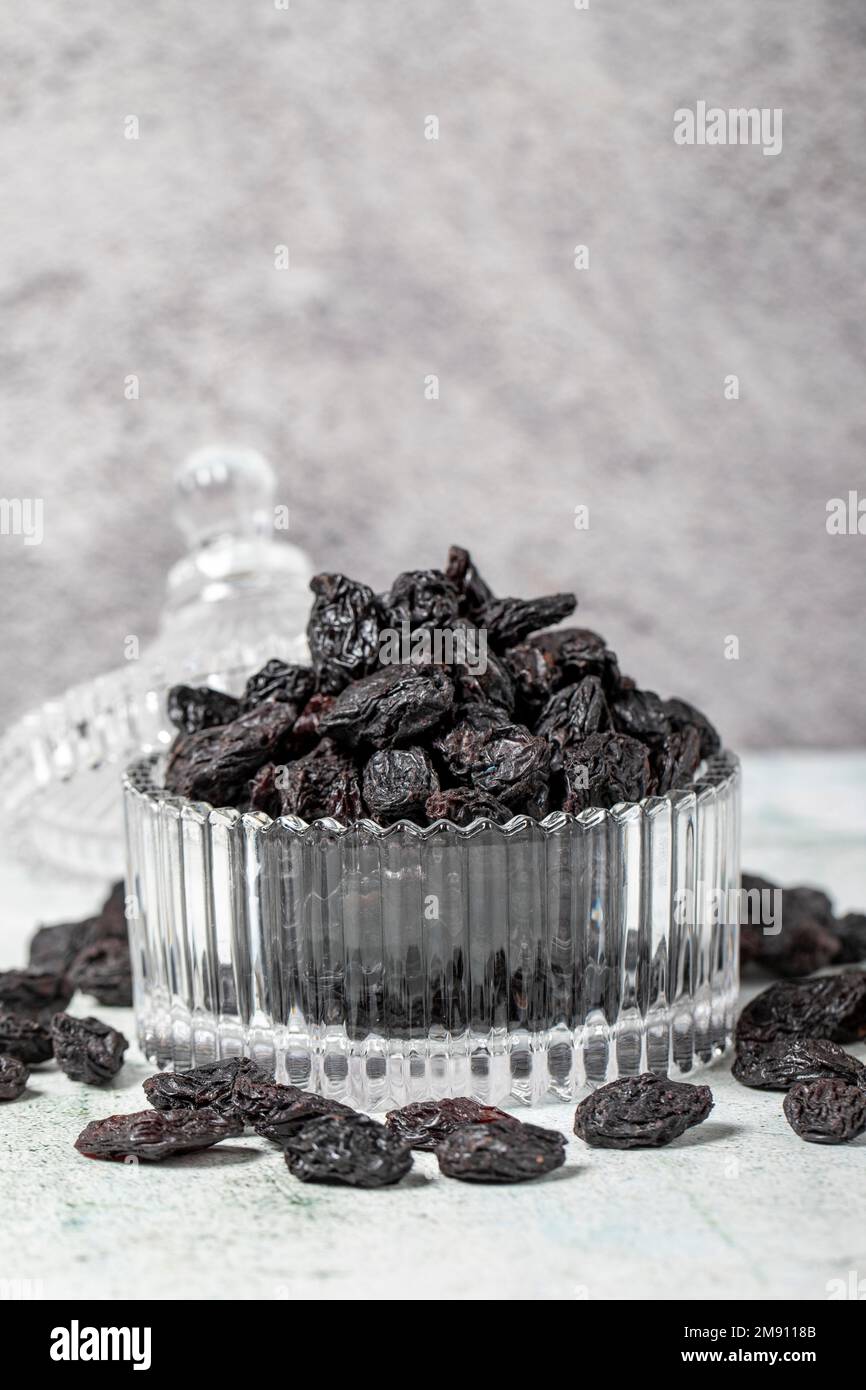 Dried black grapes on stone background. Dried grapes in glass bowl