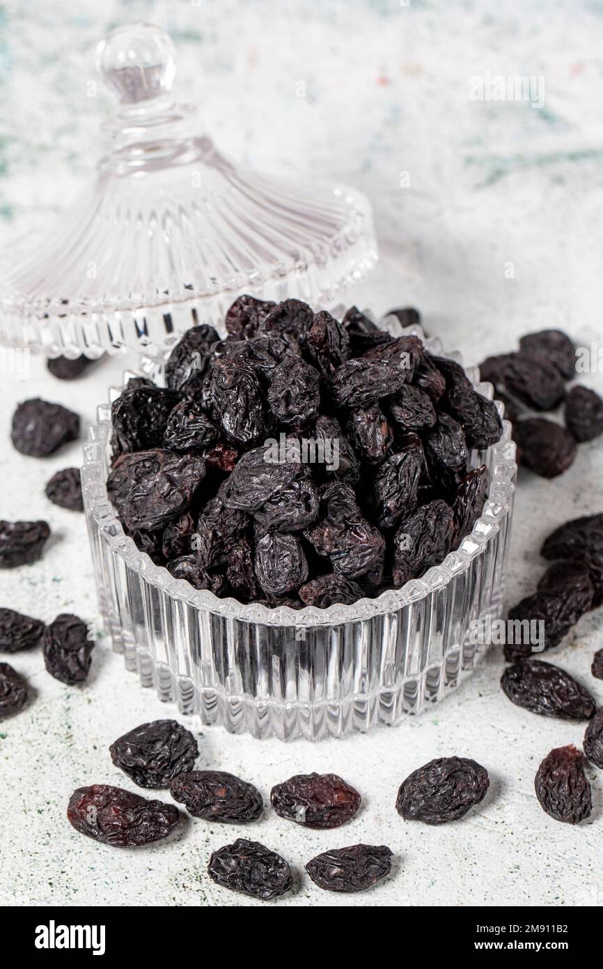 Dried black grapes on stone background. Dried grapes in glass bowl
