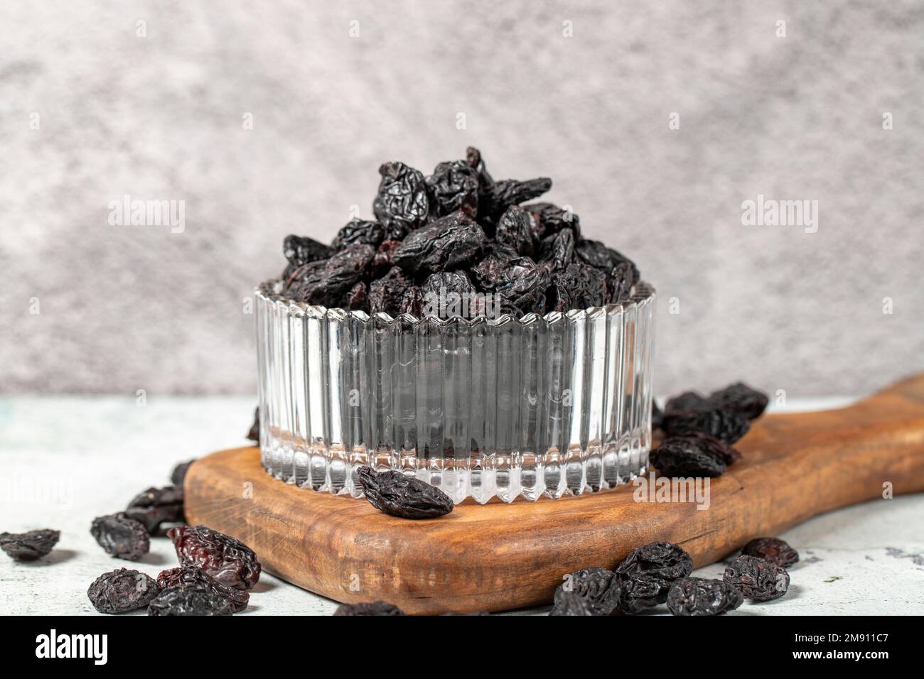 Dried black grapes on stone background. Dried grapes in glass bowl