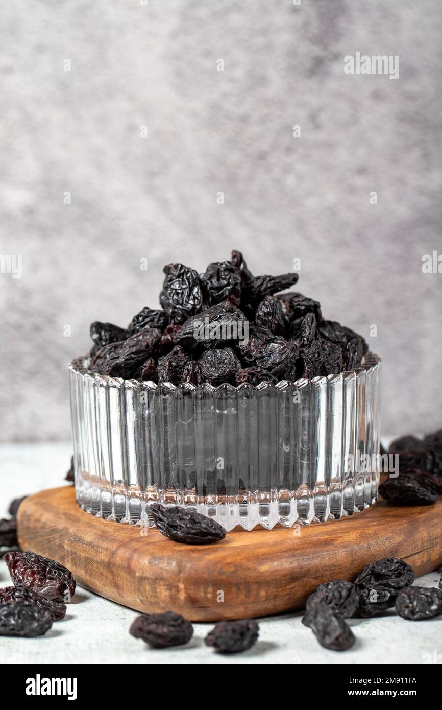 Dried black grapes on stone background. Dried grapes in glass bowl