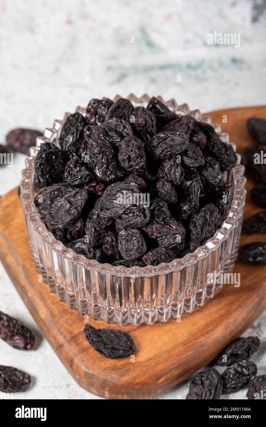 Dried black grapes on stone background. Dried grapes in glass bowl