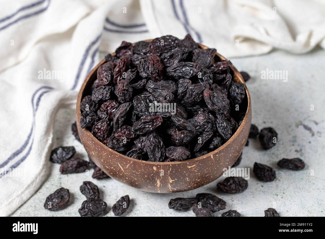 Dried black grapes on stone background. Dried grapes in coconut bowl