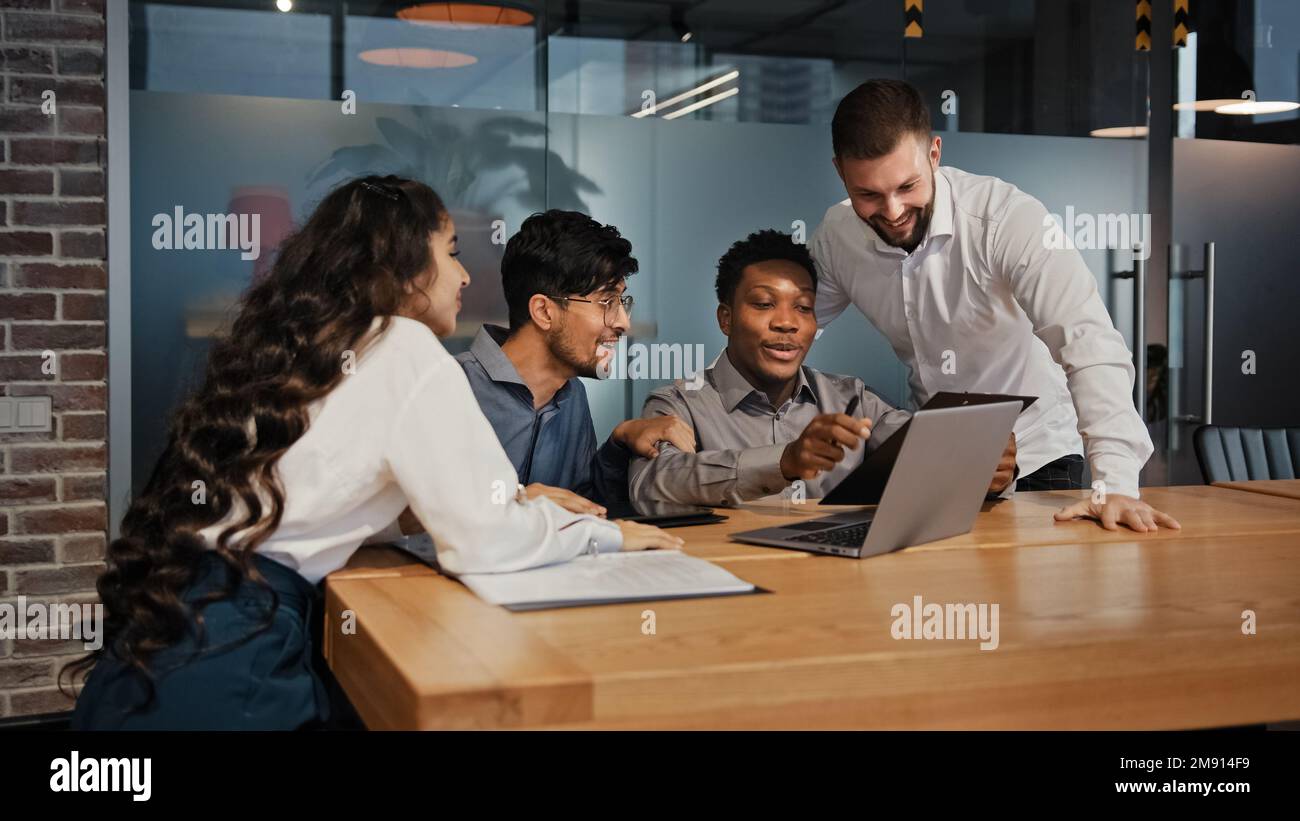 Business partners multiracial team group people workers in office looking at laptop happy with internet work success project opportunity multinational Stock Photo