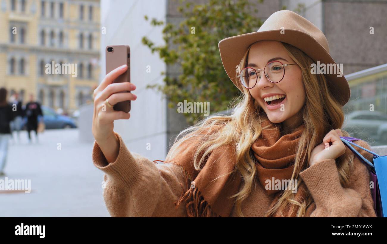 Caucasian girl vlogger blogger recording video blog vlog with smartphone after shopping in city. Smiling woman taking photo on mobile camera female Stock Photo